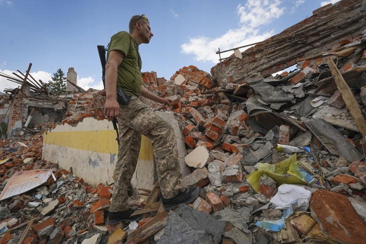 Ukrán katona egy orosz rakétatámadásban megsemmisült iskolaépület romjai között a kelet-ukrajnai Harkivban 2022. július 5-én. Fotó: MTI/AP/Andrii Marienko