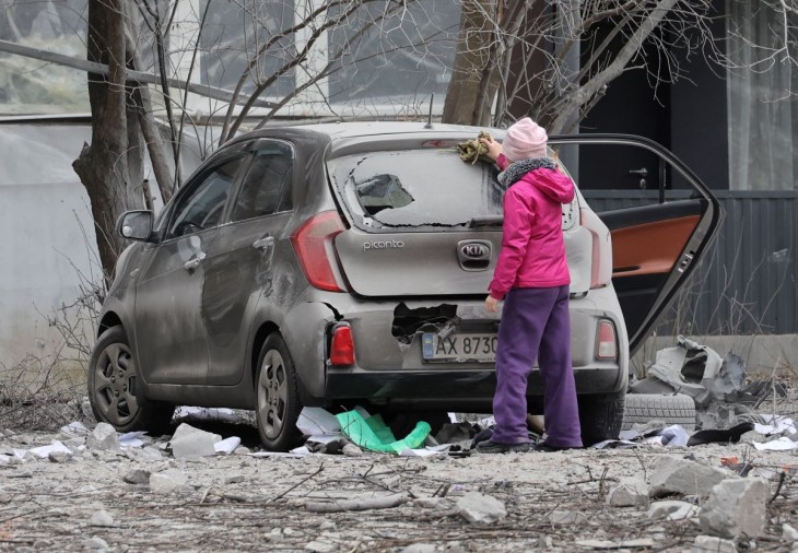 Megsérült autó mellett egy lány Harkivban 2023. december 8-án, miután orosz rakétatámadás érte a kelet-ukrajnai várost. Legalább egy ember megsebesült. Fotó: MTI/EPA