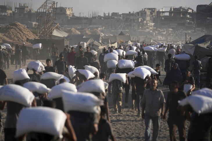 Humanitárius segélyként érkezett lisztet cipelnek palesztin emberek Gáza városába a Gázai övezet északi részéből 2025. július 31-én