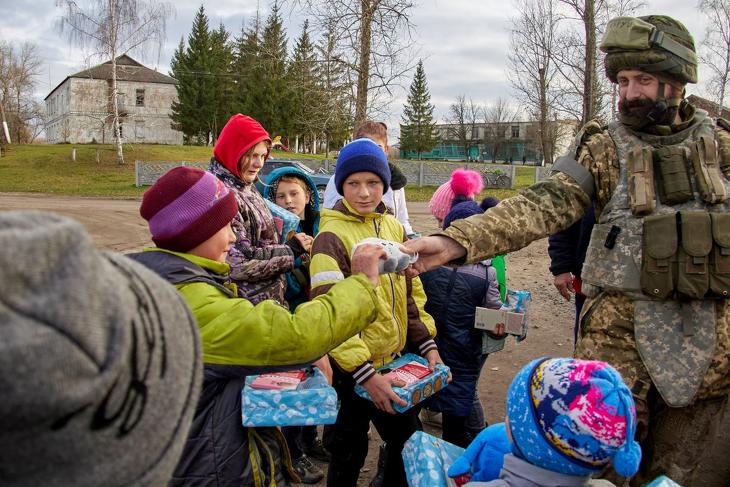 Ukrán katona édességet és játékokat ajándékoz gyerekeknek a kelet-ukrajnai Harkiv közelében fekvő, az orosz hadseregtől a közelmúltban visszafoglalt Kupjanszkban 2022. november 7-én. Fotó: MTI/AP