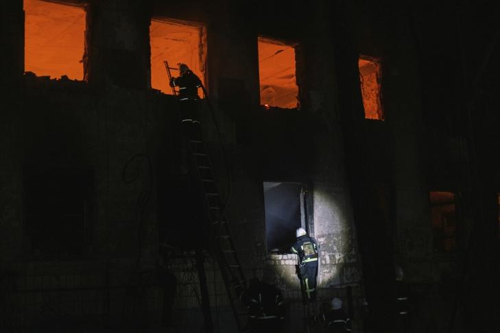 Lángoló épületnél tűzoltók a dél-ukrajnai Mikolajivban egy orosz tüzérségi támadás után. Fotó: MTI/AP/George Ivanchenko