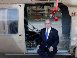 Benjámin Netanjahu izraeli miniszterelnök egy katonai szállítóhelikopter ajtajában ül egy izraeli légibázison tett korábbi látogatáson, 2023. július 5-én. Fotó: MTI/EPA/Abir Szultan