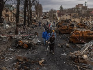 Helyi lakosok egy szétlőtt utcán az orosz haderőtől visszafoglalt Bucsában, Kijevtől északnyugatra  2022. április 6-án. Bucsa a háború egyik szimbóluma lett, az orosz csapatok háborús bűnnel felérő mészárlást  követtek el itt helyszíni vizsgálatok szerint. Fotó:  EPA/ROMAN PILIPEY      