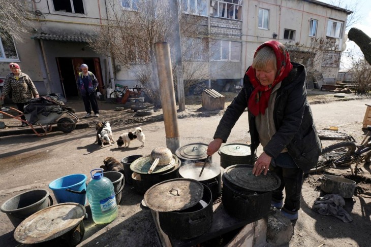 Ételt főz egy helybeli asszony a felszabadított ukrajnai faluban, Ruszki Tiskiben 2023. március 27-én. A tél elmúltával sok lakos visszatér a Harkivi területen felszabadított településekre, hogy helyrehozzák, újjáépítsék házukat. Fotó: MTI/AP