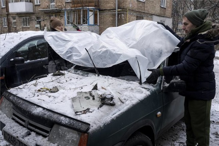Műanyag fóliával letakarja autóját egy pár egy orosz rakétatámadás után Kijevben 2022. december 14-én. Fotó: MTI/AP/Jevhen Maloletka