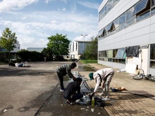 Menedékkérők mosogatnak az utcán Párizs egyik külvárosi részén