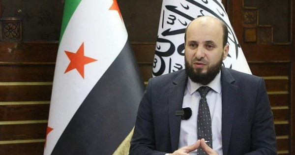 Az új miniszterelnök Mohamad al-Basír a szír és az iszlamista zászló előtt beszél