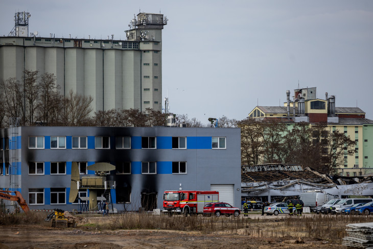 Az LPP Holding cseh hadiipari vállalat kiégett rakatárépülete előtt tűzoltók és rendőrök a csehországi Pardubicében egy éjszakai tűz után, 2026. március 20-án