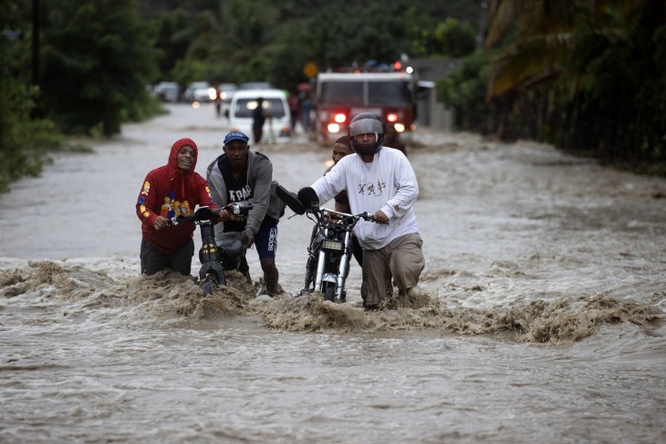 Emberek kelnek át egy elárasztott úton a heves esőzések következtében a dominikai köztársaságbeli San Jose de Ocoában, 2023. november 18-án. Egy ember eltűnt, legalább 1522 embernek kellett elhagynia otthonát, és egy híd is összeomlott a Dominikai Köztársaságban az intenzív esőzések miatt, amelyek okán a hatóságok az ország 32 tartományából 30-ban riasztást, 11-ben pedig vörös fokozatú riasztást rendeltek el. Fotó: EPA / Orlando Barria