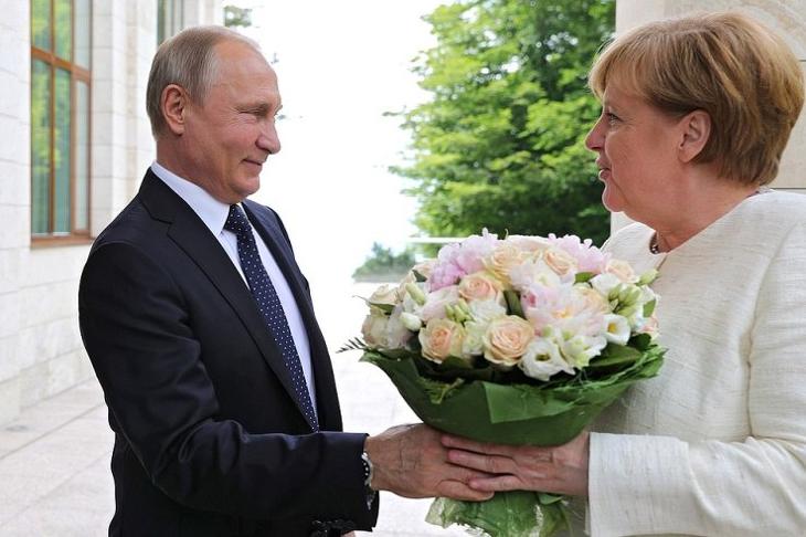 Vlagyimir Putyin nyújt át egy virágcsokrot Angela Merkelnek 2018. május 18-án Szocsiban, ahol az Északi Áramlat 2-ről tárgyaltak. (Forrás: www.kremlin.ru/Wikipédia)